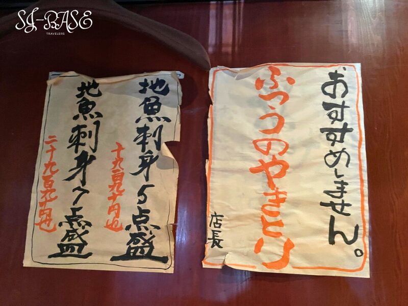 まるげんの店内に貼られた手書きの貼り紙。ユーモアと個性が感じられる筆文字メニュー。