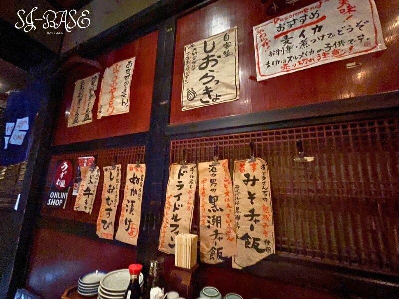 楽味家まるげんの店内に並ぶ手書きメニュー。味のある筆文字が印象的な壁面。