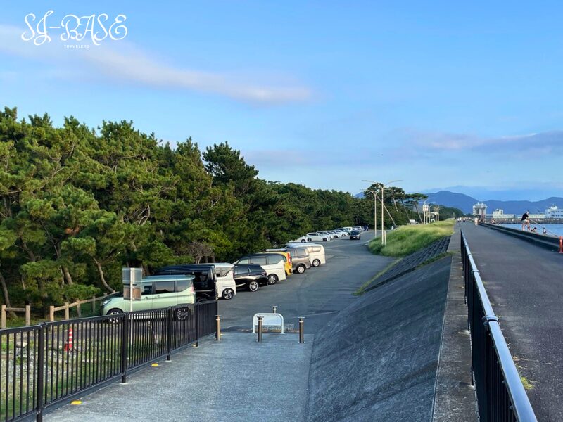千本浜海岸の駐車場と堤防沿いの道。釣りや散歩に訪れる人の車が並ぶ。