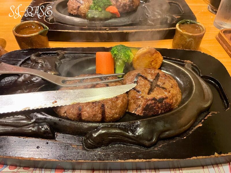 げんこつハンバーグを切り分ける瞬間。熱々の鉄板から立ちのぼる湯気と香ばしい香り
