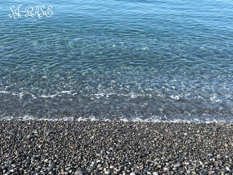 千本浜の透き通った海水と丸い石が並ぶ浜辺のアップ。