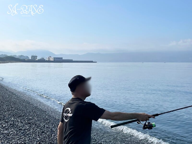 千本浜海岸で釣りを楽しむ男性。静かな朝の海に糸を投げ込む様子。