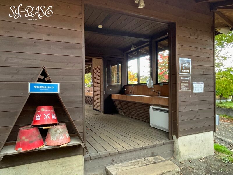 北軽井沢スウィートグラスの炊事場。屋根付きのシンクと作業台があり、清潔に保たれた共有キッチン。