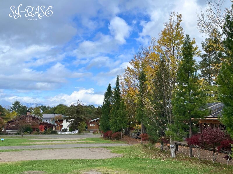 秋のスウィートグラス、青空の下に並ぶ木立とコテージの風景