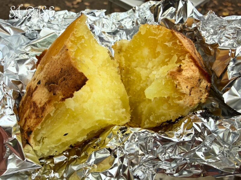 焚き火で焼き上げた焼き芋。ホクホクに割れた黄金色の中身が湯気を立てる。