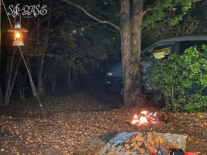 ランタンと焚き火が灯るスウィートグラスの夜。木々の間にやさしい灯りがともる。